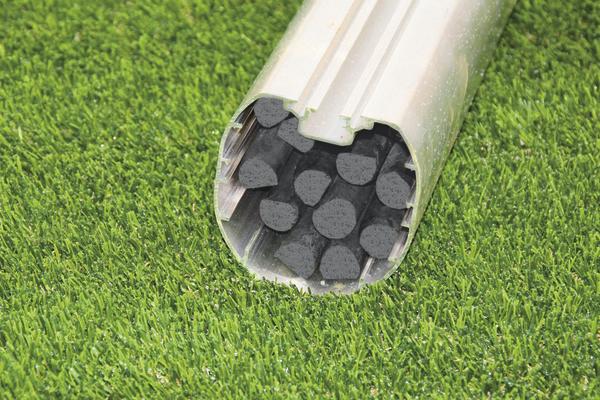 Querschnitt eines Aluminiumrohrs mit Kohlefaserstäben auf grünem Kunstrasen.