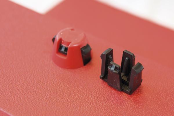 Roter und schwarzer Kunststoffverschluss auf rotem strukturiertem Untergrund, Nahaufnahme.