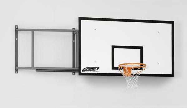 Basketballanlage mit Korb und weißem Brett von Sportco, montiert an einer Hallenwand und zur Seite geschwenkt (in Ruheposition).