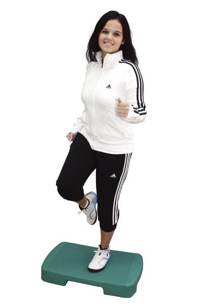 Frau in Adidas-Sportoutfit macht Step-Aerobic auf grünem Stepper.
