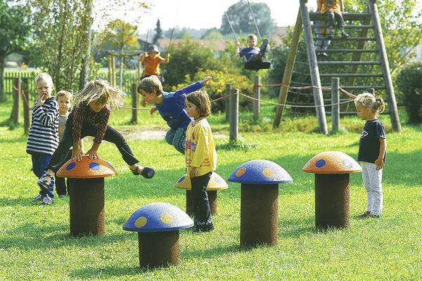 Kinder spielen auf bunten Pilzspielgeräten und Schaukeln im sonnigen Park.