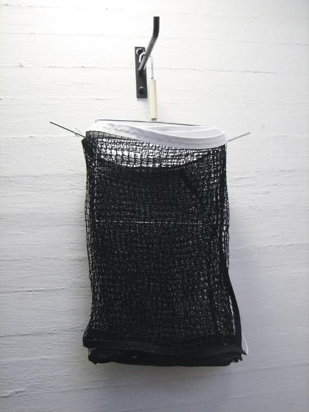 Schwarzes Netz zum Trocknen an einer weißen Wand aufgehängt.