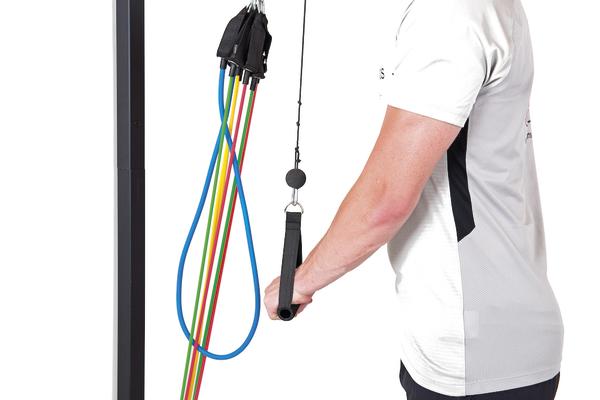 Person trainiert mit bunten Widerstandsbändern an Fitnessgerät für Krafttraining.