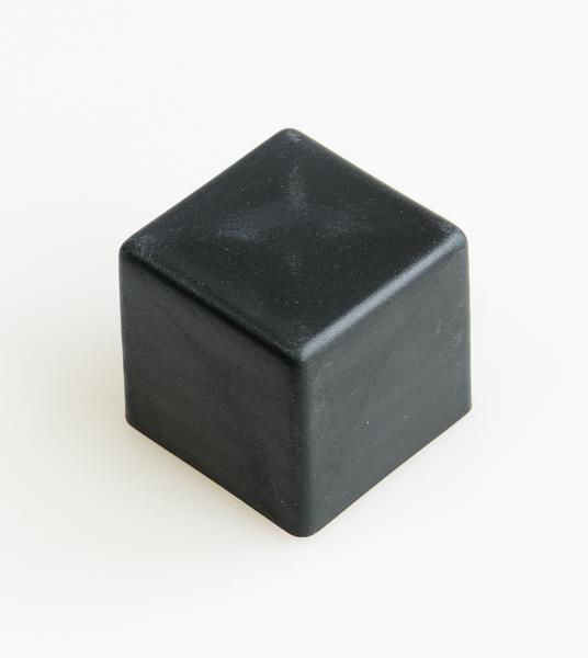 Schwarzer Würfel aus Kunststoff auf weißem Hintergrund, minimalistisches Design.