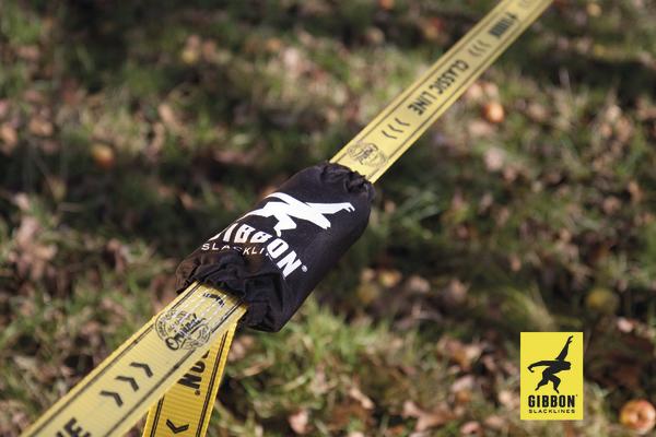 Gelbe Gibbon Slackline mit schwarzer Schutzhülle auf Gras im Freien.