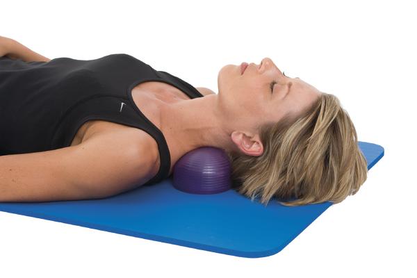 Frau entspannt auf Gymnastikmatte mit Nackenstütze aus Gymnastikball für Nackenmassage.