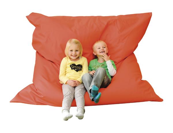 Kinder sitzen lachend auf großem orangenem Sitzsack vor weißem Hintergrund.