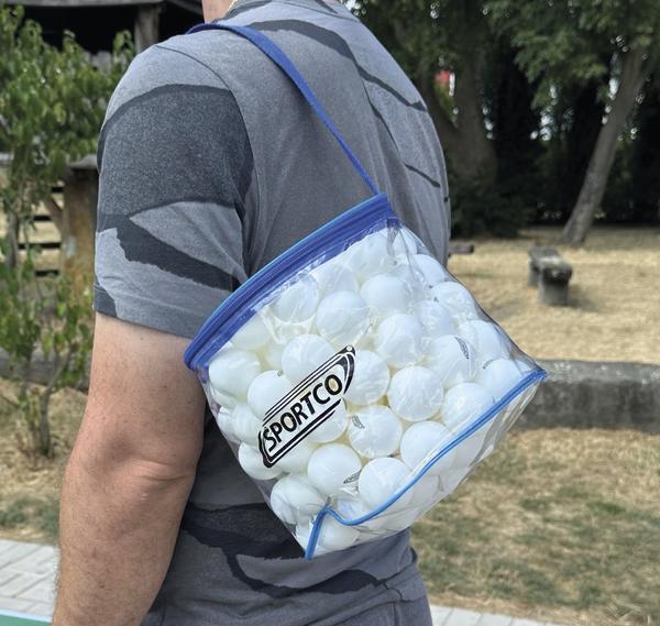 Person trägt das Sportco Tischtennisbälle-Set mit weißen Tischtennisbällen in transparenter Schultertasche mit blauem Reißverschluss.