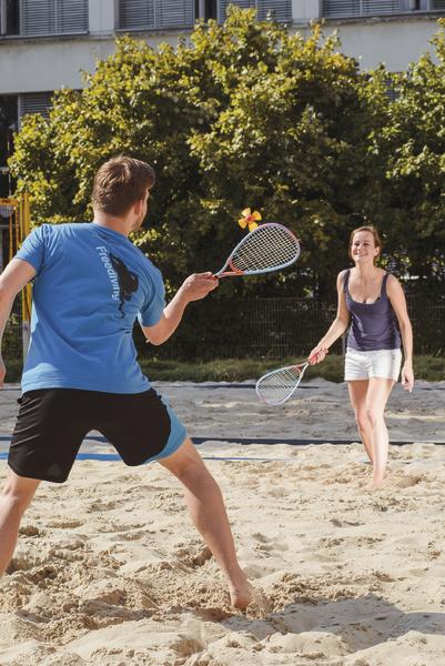 Mann und Frau spielen Federball im Sand bei sonnigem Wetter.
