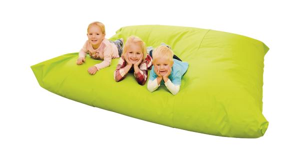 Drei Kinder liegen lächelnd auf einem großen grünen Sitzsack, weißer Hintergrund.