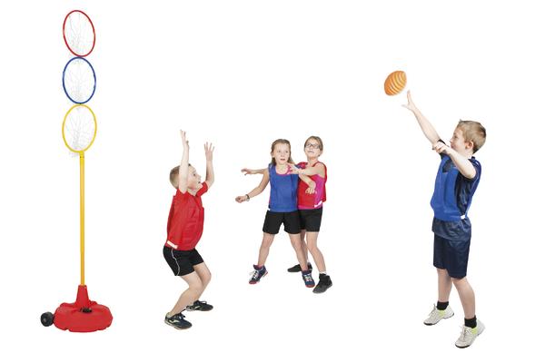 Dreifacher Basketballkorb für Kinder mit roten, blauen und gelben Ringen. Drei Kinder spielen Basketball, zwei verteidigen, ein Kind wirft den Ball.