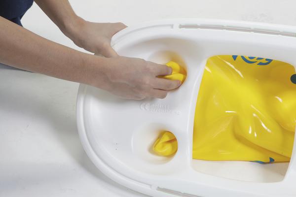 Hände befestigen gelbe Ventile an einem weißen aufblasbaren Schwimmring.