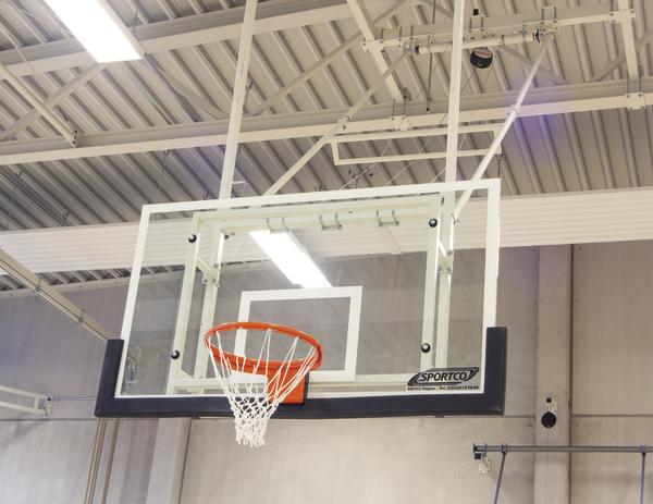 Basketballkorb mit Netz in moderner Sporthalle unter Hallenbeleuchtung.