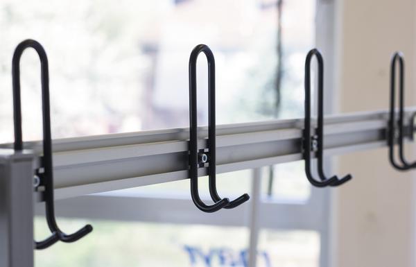 Moderner Garderobenhaken aus Metall an einer Wandhalterung in Innenraum.