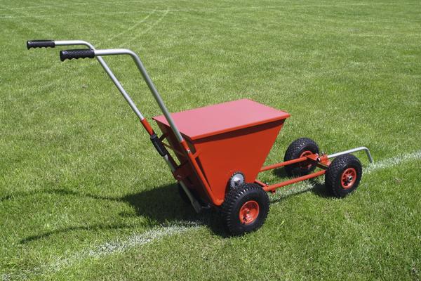 Roter Linienmarkierer auf grünem Rasen zum Markieren von Sportfeldern.