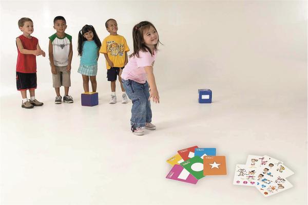 Fünf Kinder spielen ein Lernspiel mit bunten Karten und Würfeln auf weißem Hintergrund.