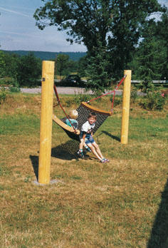 Outdoor-Hängematte bzw. Netzschaukel zwischen stabilen Holzpfosten, geeignet als Spiel- und Ruheelement für Außenbereiche.