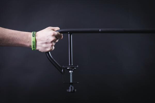 Hand hält schwarzen Mikrofonarm mit Klemme vor dunklem Hintergrund.