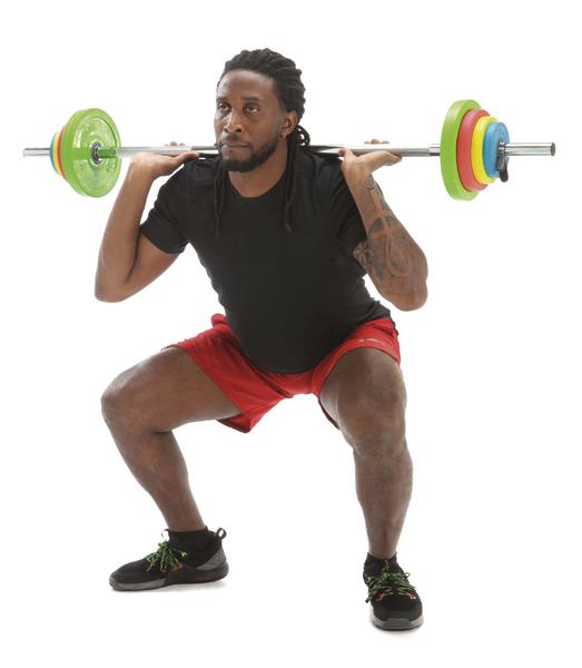 Mann macht Kniebeuge mit Langhantel und bunten Gewichtsscheiben im Fitnessstudio.