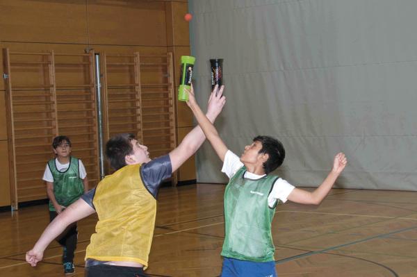 Kinder spielen in der Turnhalle mit Schlägern und Ball, sportliche Aktivität im Innenraum.