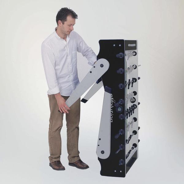 Mann klappt einen Tischkicker zusammen und stellt ihn platzsparend hochkant auf.