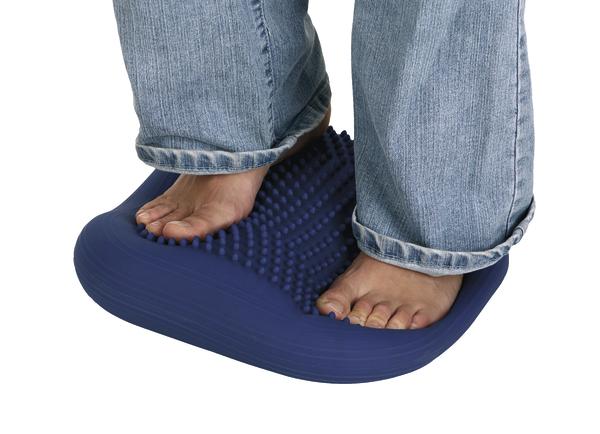 Barfuß auf blauem Noppen-Fußmassagegerät stehend, Jeanshose sichtbar, weißer Hintergrund.