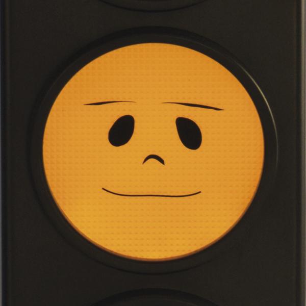 Gelbes Ampelsignal mit neutralem, leicht lächelndem Gesicht als Symbol für vorsichtiges Warten.