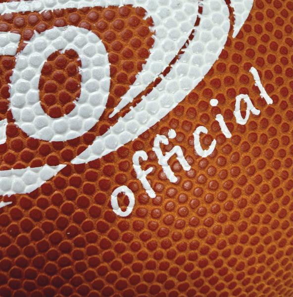 Detailaufnahme eines braunen SPORTCO Official Gummi-Footballs mit stark genoppter Oberfläche und weißem Logo-Aufdruck im klassischen American-Football-Design
