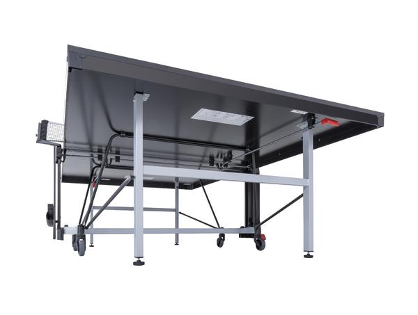 Klappbarer Tischtennistisch mit Metallgestell und Rollen, von unten fotografiert, weißer Hintergrund.