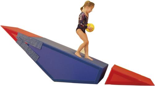 Kind mit gelbem Ball auf blau-rotem Kletterspielgerät in Turnkleidung vor weißem Hintergrund