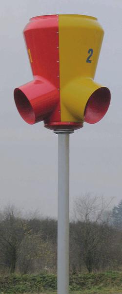 Rotes und gelbes Schallschutzgerät auf Pfahl im Freien, nummeriert mit "2".