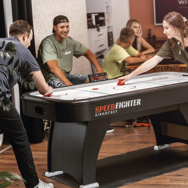 Zwei Personen spielen Airhockey an einem Tisch in Innenraumumgebung