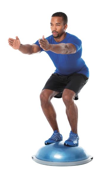 Mann macht Balance-Übung auf halbkugelförmigem Balance-Board in Sportkleidung.