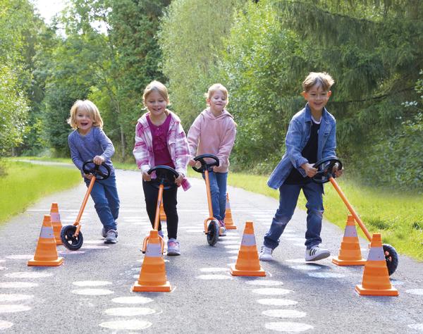 Kinder fahren mit Rollern auf einem Parcours mit orangen Verkehrskegeln im Park.