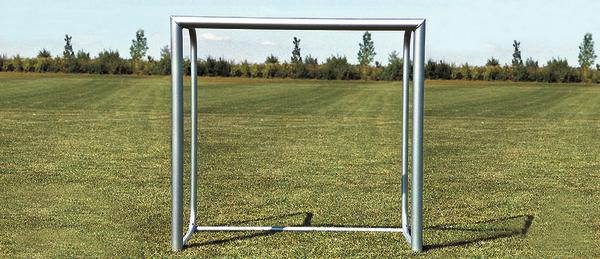 Leeres Fußballtor auf grünem Rasenfeld unter klarem Himmel