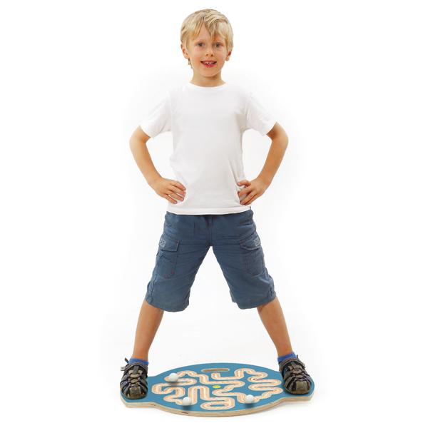 Junge steht auf einem Holzlabyrinth-Spiel, trägt weißes T-Shirt und blaue Shorts.