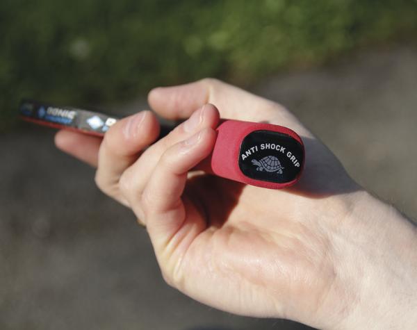 Hand hält roten Schlägergriff mit Anti Shock Grip Aufschrift und Schildkröten-Logo.