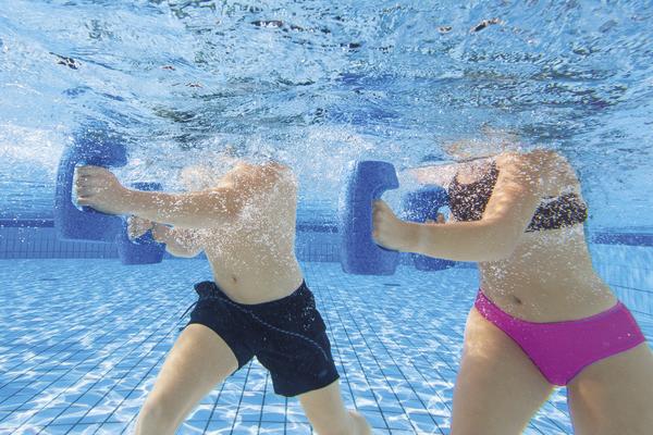 Unterwasseraufnahme von zwei Personen beim Aquafitness-Training mit Schwimmbrettern im Pool.