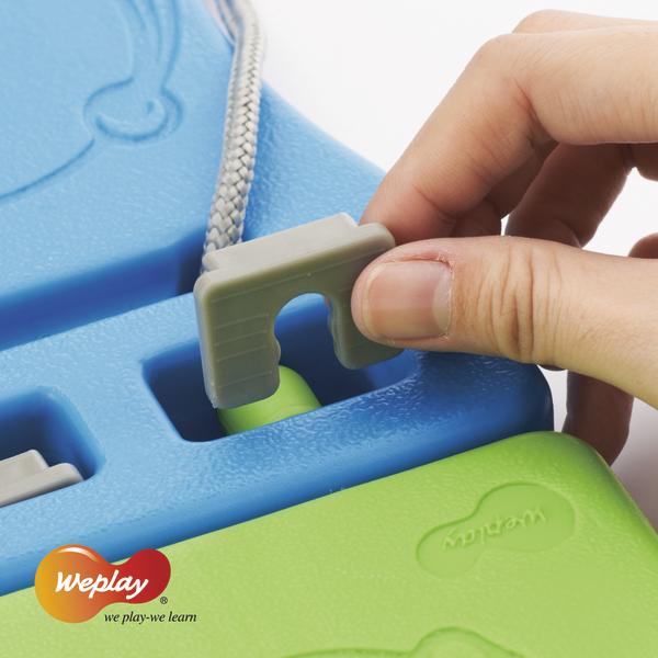 Hand steckt grauen Stecker in blau-grünes Weplay Lernspielzeug mit Schnur.