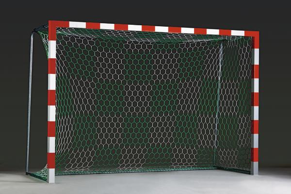 Handballtor mit rot-weißem Rahmen und grünem Netz auf grauem Boden vor dunklem Hintergrund.