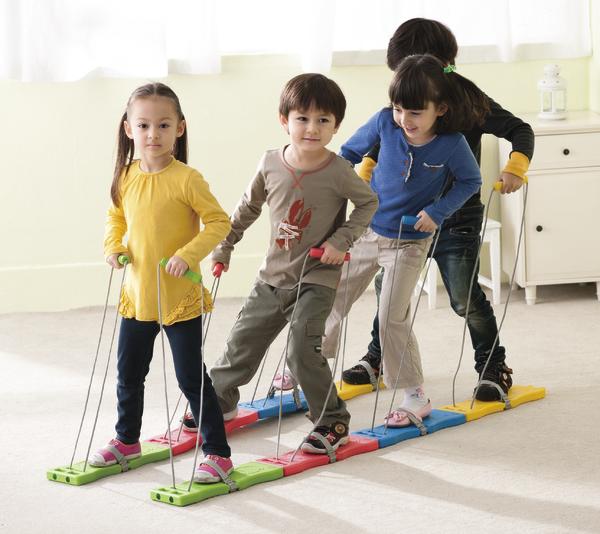 Kinder spielen gemeinsam mit bunten Laufbrettern im Innenraum, Teamaktivität und Bewegung.