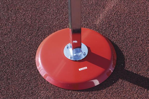 Roter Standfuß mit Metallstange auf rotem Gummibelag, Nahaufnahme im Freien.