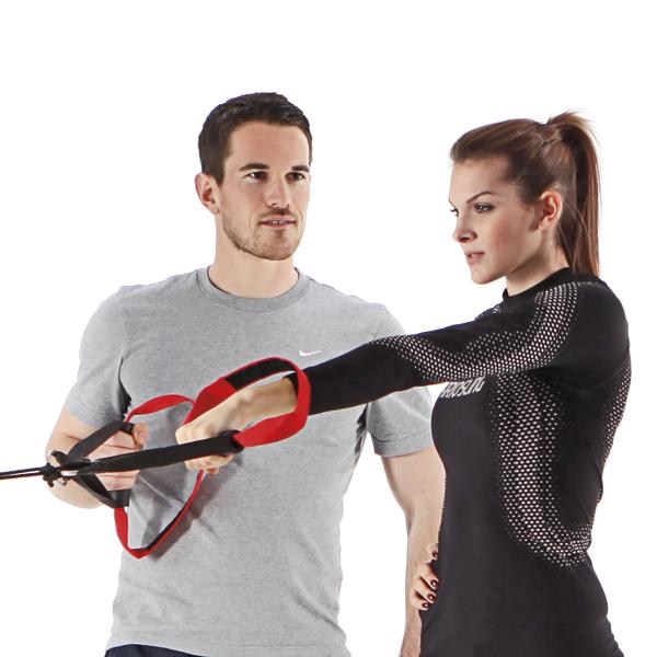 Mann trainiert Frau mit Widerstandsband für Krafttraining im Fitnessstudio.