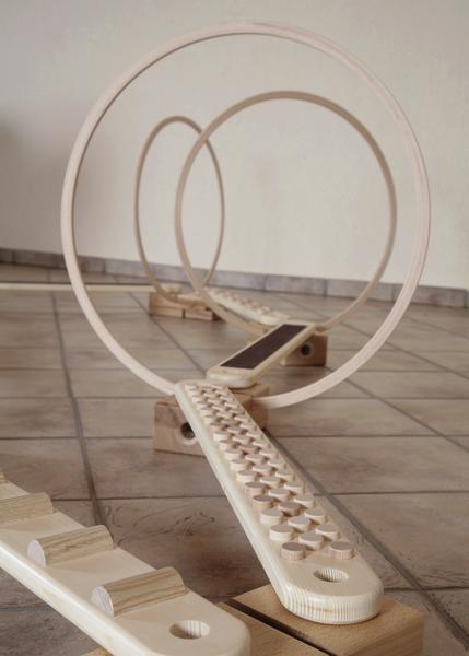 Geschwungene Holzspielbahn mit Ringen auf Fliesenboden, modernes Design für Geschicklichkeitsspiele.