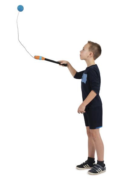Junge spielt mit einem Ball an einer Schnur an einem Schläger, weißer Hintergrund.