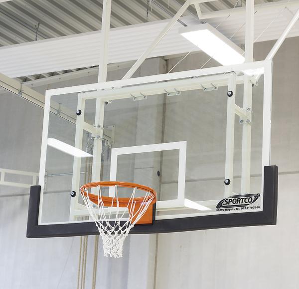 Basketballkorb mit transparentem Rückbrett in moderner Sporthalle, Sportgerät für Basketballspiel.