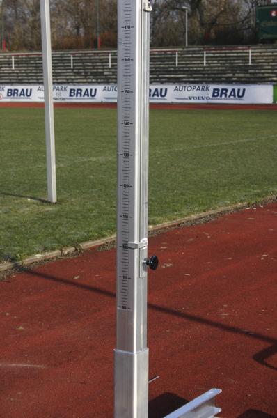 Hochsprunglattenhalter mit Höhenmesser auf roter Laufbahn im Stadion.