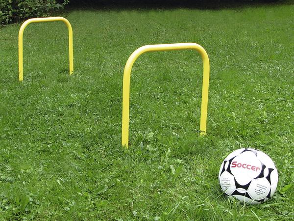 Gelber Fußball-Trainingsparcours mit Ball auf grünem Rasen im Freien.