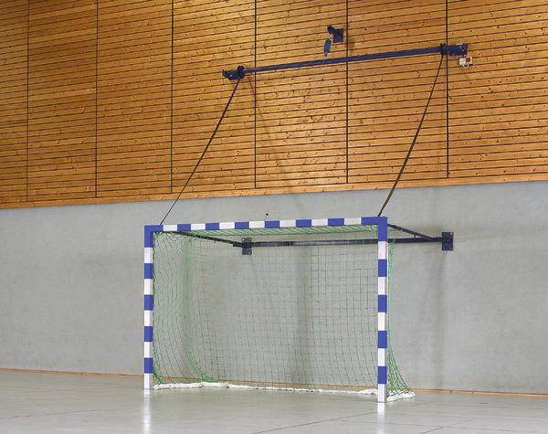 Handballtor mit blau-weißen Pfosten und grünem Netz in einer Sporthalle mit Holzwand.