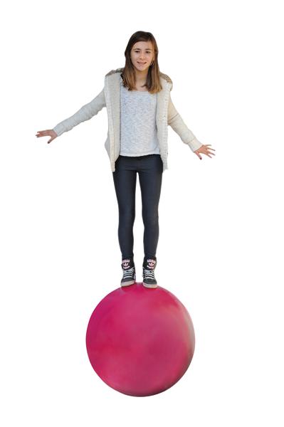 Mädchen balanciert auf großem roten Ball vor weißem Hintergrund.